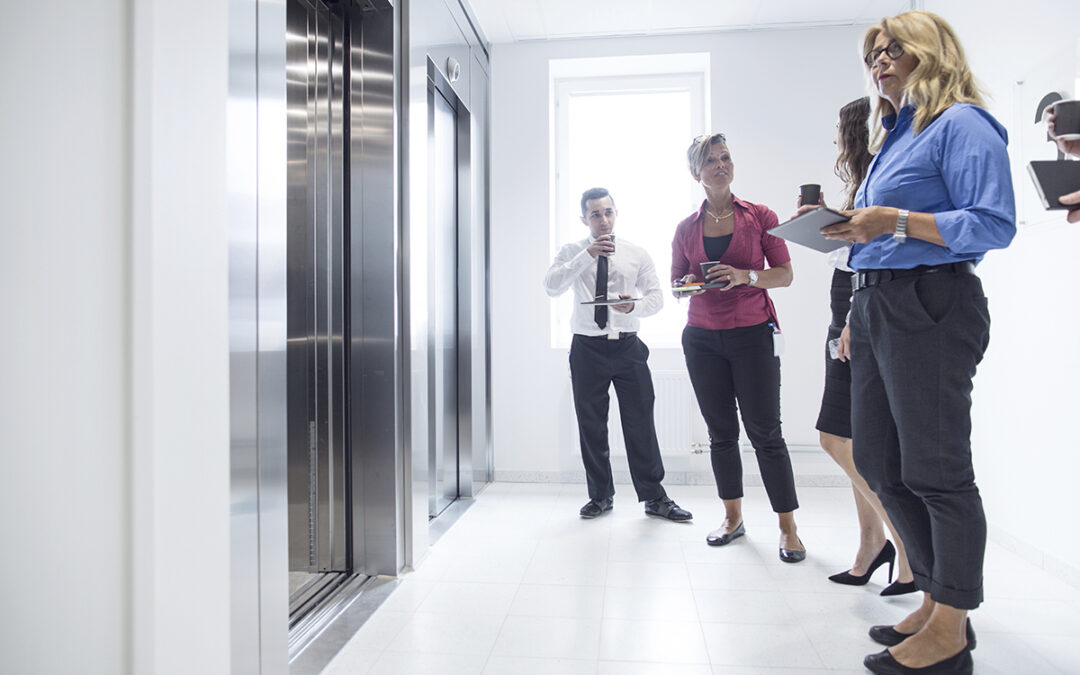 Colleagues having a casual coffee break by the elevator